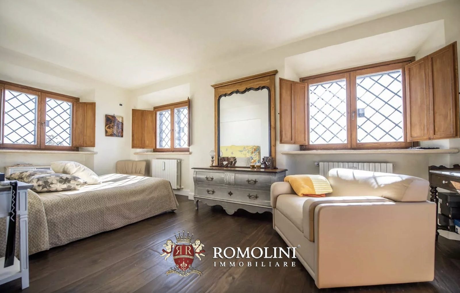 Bedroom with dark hardwood floors, wooden shutters, and diamond-leaded windows in the Monte Argentario lighthouse villa