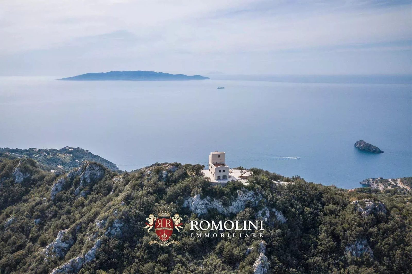 Aerial view of the former lighthouse villa on a rocky summit of Monte Argentario with Giglio Island and the Tyrrhenian Sea beyond