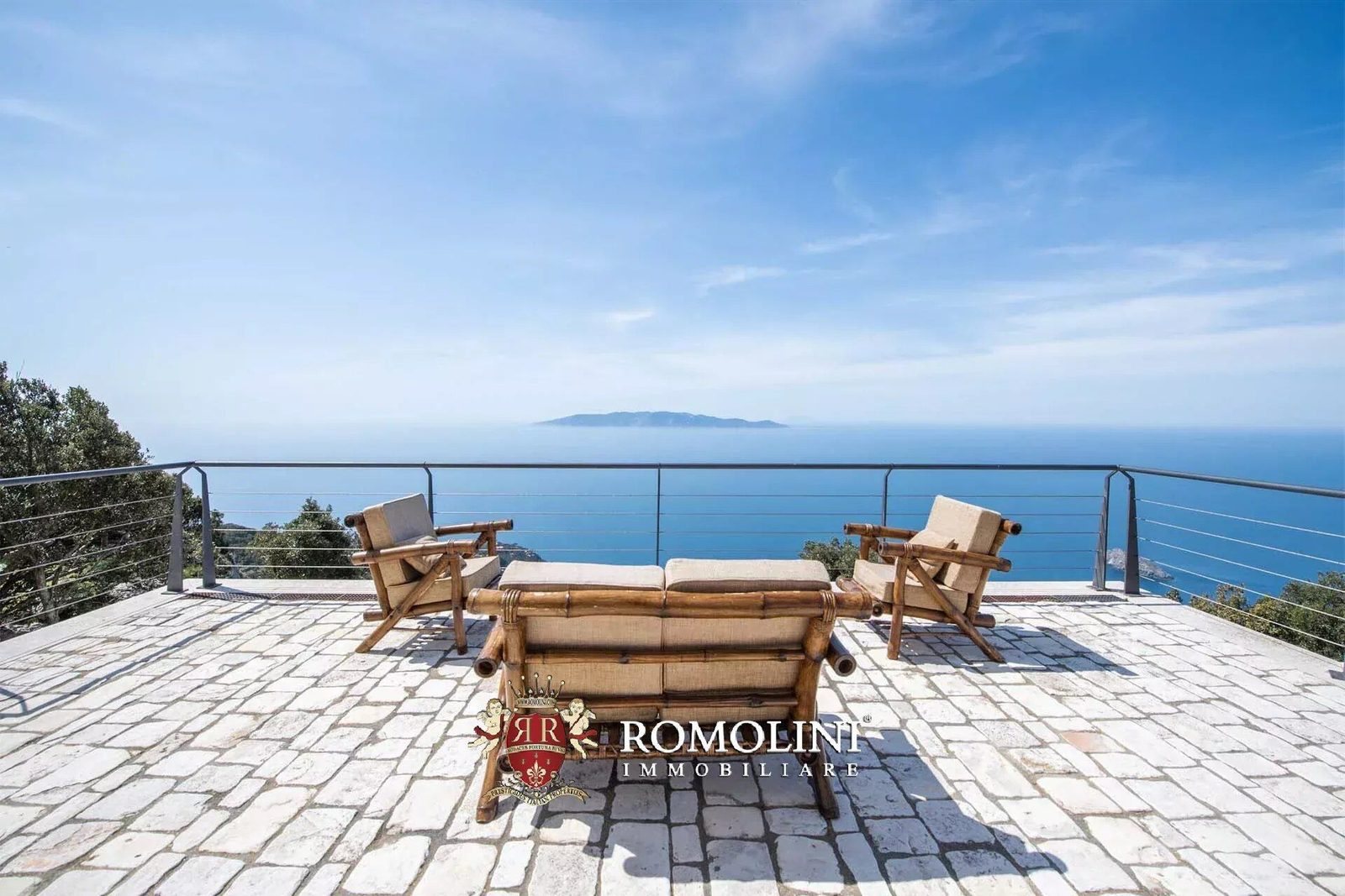 Paved stone terrace with bamboo lounge furniture overlooking the Tyrrhenian Sea and Giglio Island from the former lighthouse on Monte Argentario, Tuscany