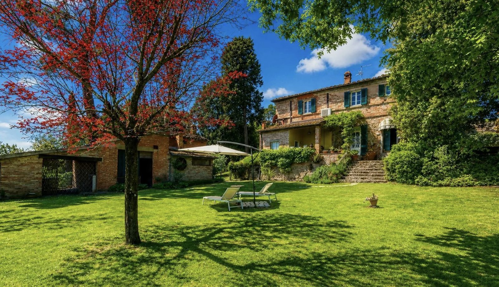 Tuscan country farmhouse with garden and lawn, the kind of property absorbing American buyer demand priced out of Milan
